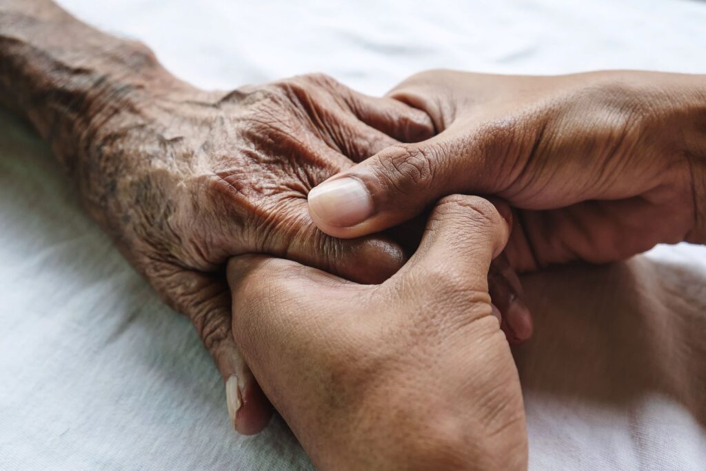 two adults holding hands for comfort