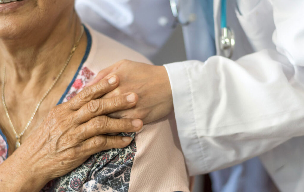 health care professional with hand on shoulder of older adult