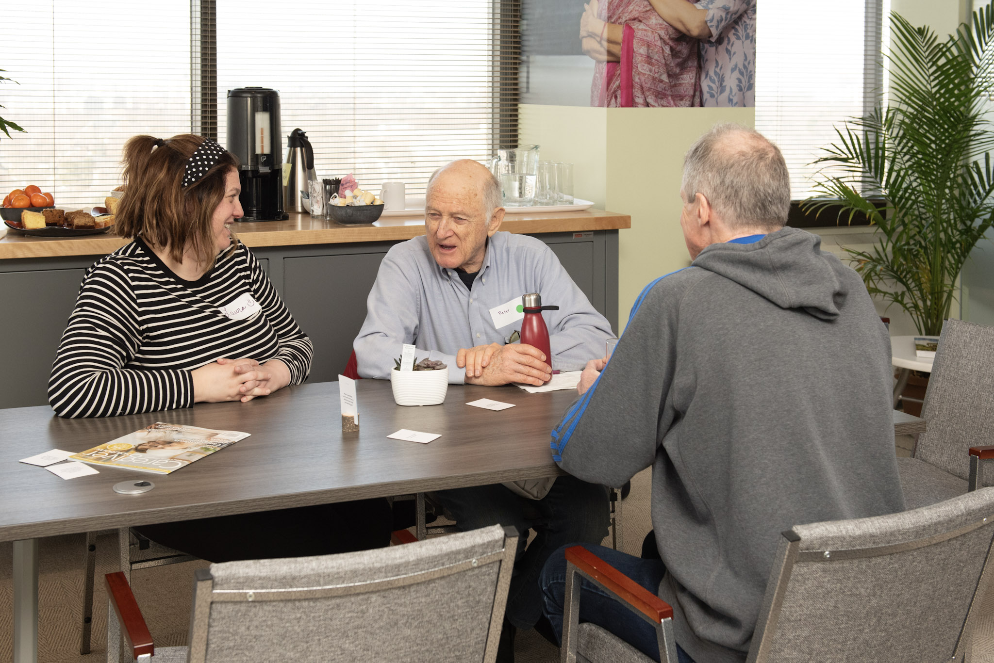 Three people sitting at a table and conversing.