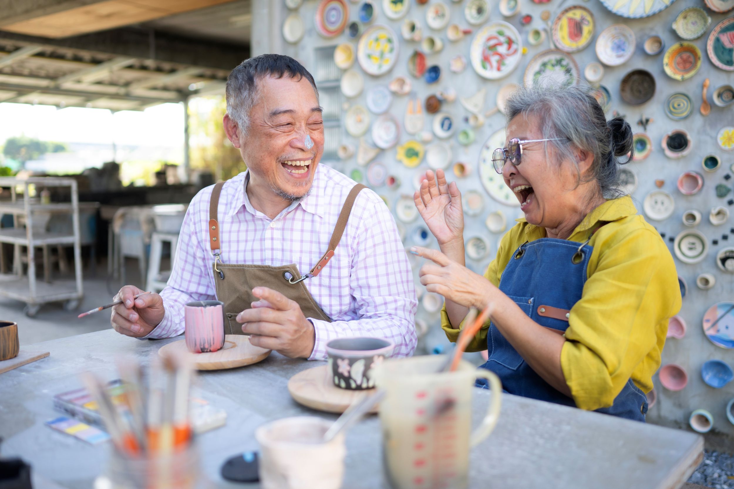 Two Asian seniors making pottery